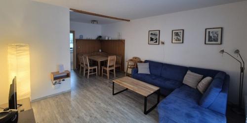 un salon avec un canapé bleu et une table dans l'établissement Ferienhaus Nr 91, Kategorie Komfort, Feriendorf Hochbergle, Allgäu, à Karlsebene