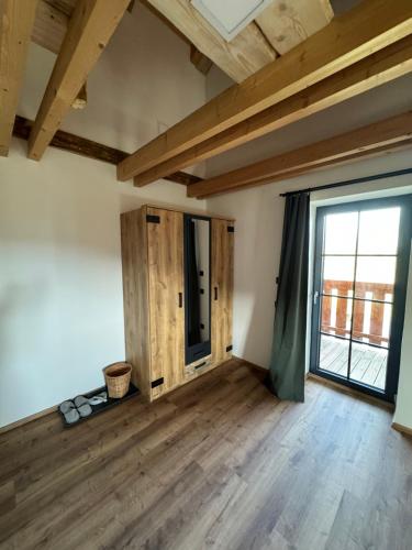 an empty room with a large window and wooden floors at Penzion Farma Žleby in České Žleby