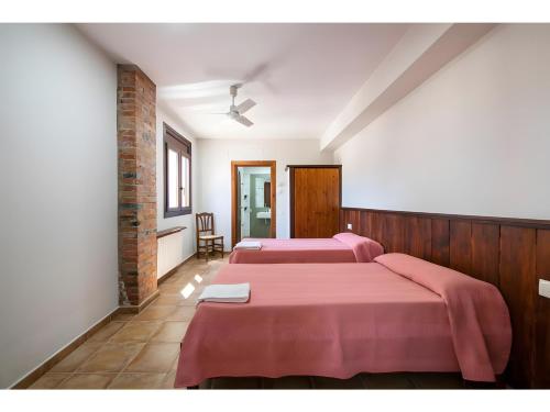 two beds in a room with pink sheets at Can Fonsu in Galliners