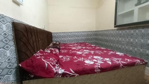 a bed with a red blanket on top of it at Shree Gopal Niketan in Mathura