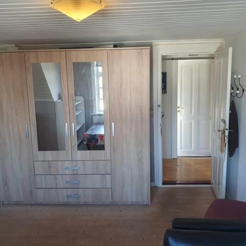 a living room with a large wooden cabinet in a room at Rundvejen Guest House in Aalborg