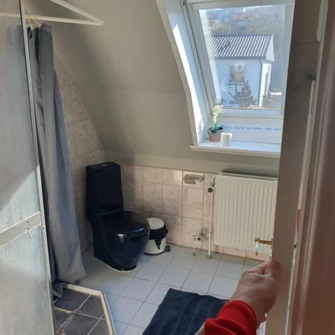 a person opening the door to a small bathroom at Rundvejen Guest House in Aalborg