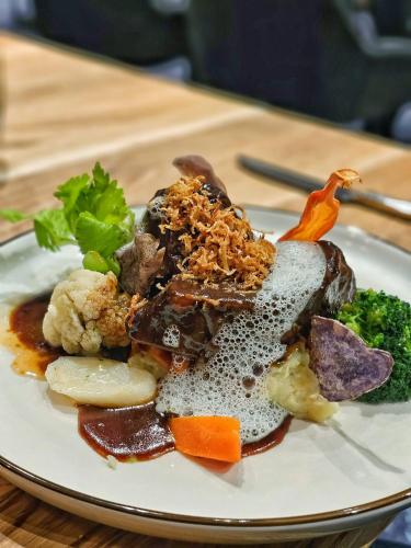a plate of food with meat and vegetables on a table at Roots Hotel Restaurant in Gomaringen