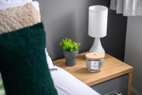 a bedside table with a lamp and a plant on it at Stylish Interior Designed Home in Crewe