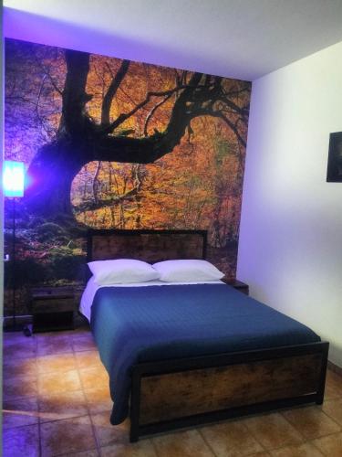 a bedroom with a bed with a tree mural on the wall at SIM residence in Maniago