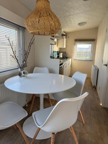 a kitchen with a white table and white chairs at Zeeuws Ibiza huisje in Kamperland