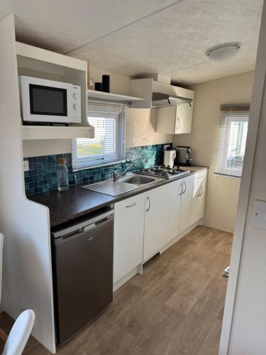 a kitchen with a sink and a microwave at Zeeuws Ibiza huisje in Kamperland