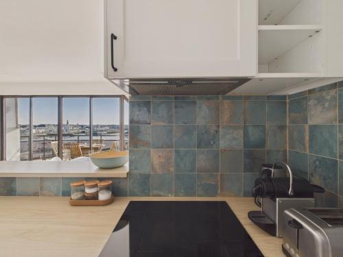 - une cuisine avec des murs carrelés bleus et des armoires blanches dans l'établissement Appartement vue mer à 350m de la plage pour 4, à Saint-Gilles-Croix-de-Vie