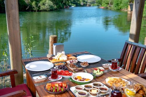 a table with food on it next to a body of water at Wineport Lodge Agva Riverside Hotel & Winery in Ağva
