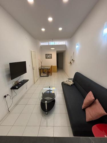 Una sala de estar con un sofá negro y un televisor. en 1 Bedroom In The Heart Of St Julians, en San Julián