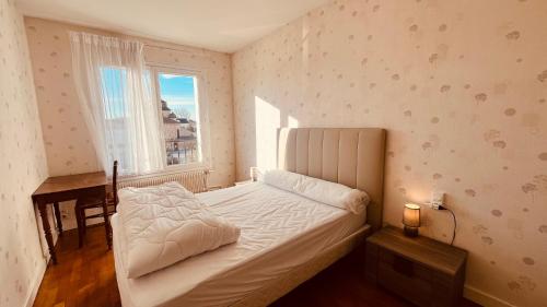 une chambre avec un lit, un bureau et une fenêtre dans l'établissement Le Centre Bourg, situation rêvée, à Saint-Jean-de-Monts