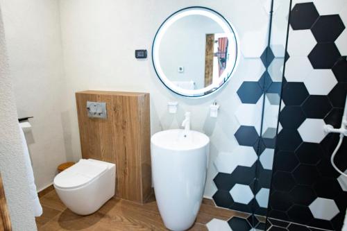a bathroom with a white toilet and a mirror at Barrique Garden in Braşov