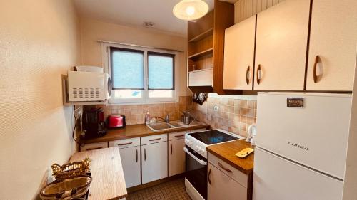 Elle comprend une petite cuisine avec un réfrigérateur blanc et une fenêtre. dans l'établissement Le Centre Bourg, situation rêvée, à Saint-Jean-de-Monts