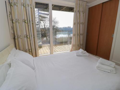 a bedroom with a white bed with a large window at The Skydeck HM50 in Cirencester