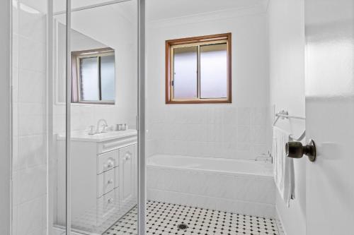 a white bathroom with a shower and a sink at Lakefront Serenity in Chittaway Point