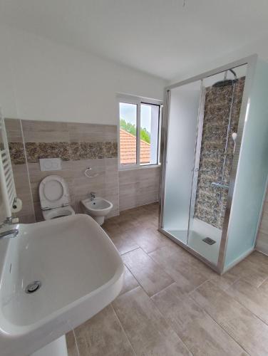 a white bathroom with a toilet and a sink at Casa Milona in Castelveccana