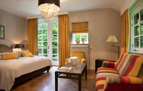 a bedroom with a bed and a table and a couch at Relais & Chateaux Hotel Landgoed Het Roode Koper in Ermelo