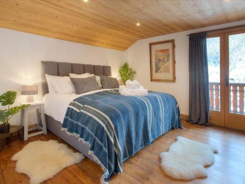 - une chambre avec un lit doté d'une couverture bleue et de 2 tapis dans l'établissement Chalet 5* 15 pers. avec spa au pied des pistes à La Clusaz - FR-1-304-308, à La Clusaz
