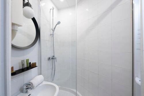 a white bathroom with a shower and a sink at Lennon by Avalon Hotel Paris Gare du Nord in Paris