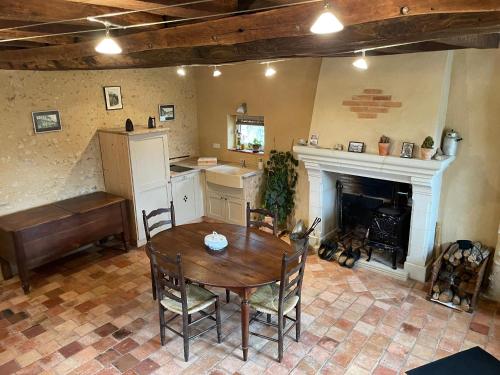 Il comprend une cuisine et une salle à manger avec une table et une cheminée. dans l'établissement Charme campagnard proche ville, jardin paisible - FR-1-410-468, à La Flèche