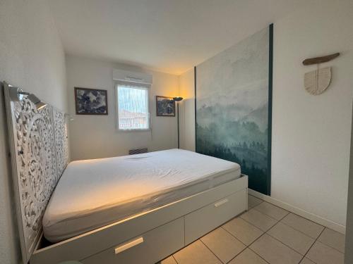 a bedroom with a bed with a large painting on the wall at Charmant T2 rénové avec terrasse proche plage - FR-1-239-1106 in Ciboure