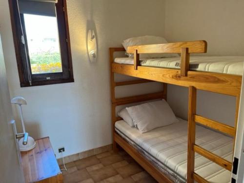 une chambre avec deux lits superposés et une fenêtre dans l'établissement Appartement RDC 2 chambres, terrasse, à 200m plage, parking, animaux admis - FR-1-749-89, au Cap d'Agde