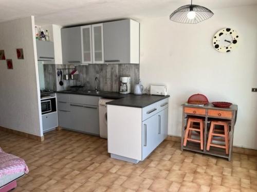 une cuisine avec des armoires blanches et un comptoir dans l'établissement Appartement RDC 2 chambres, terrasse, à 200m plage, parking, animaux admis - FR-1-749-89, au Cap d'Agde