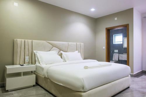 a bedroom with a large white bed with a headboard at Aylane Aparth Hotel in Nampula