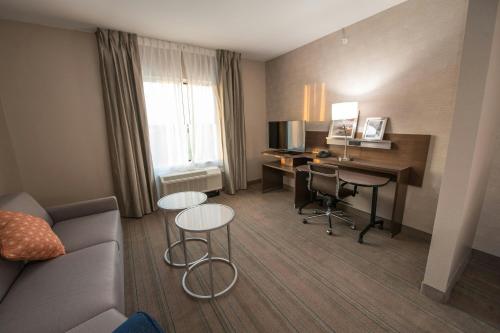 a hotel room with a desk and a table and chairs at Fairfield Inn & Suites by Marriott Huntsville in Huntsville