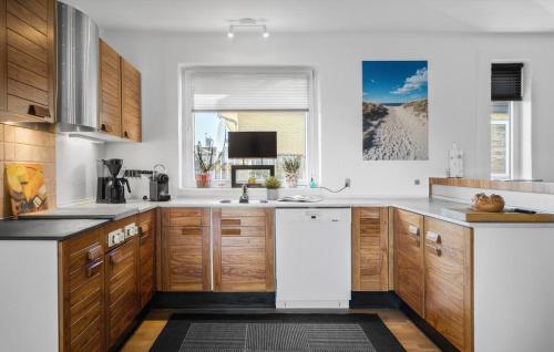 a kitchen with wooden cabinets and a white counter top at Amazing Home In Thyborøn With Sauna in Thyborøn