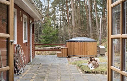 un cane seduto accanto a una vasca idromassaggio fuori da una casa di 5 Bedroom Nice Home In Hadsund a Hadsund