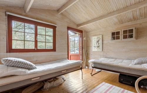 two beds in a room with wooden walls and windows at 3 Bedroom Stunning Home In Glesborg in Glesborg