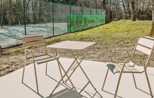 - une table et deux chaises en face d'un court de tennis dans l'établissement Suite Charmilles Avec Piscine, à Gien