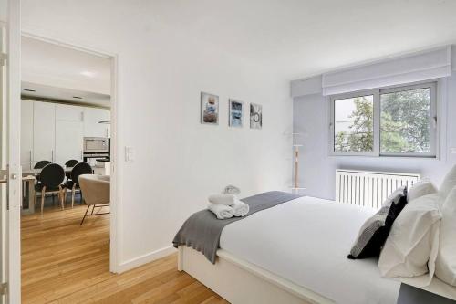 - une chambre blanche avec un lit et une salle à manger dans l'établissement Appartement spacieux - Arc de Triomphe, à Paris
