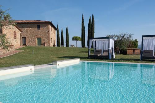 a large swimming pool with two chairs in front of a building at Villa il Castagno Wine & Resort in Siena