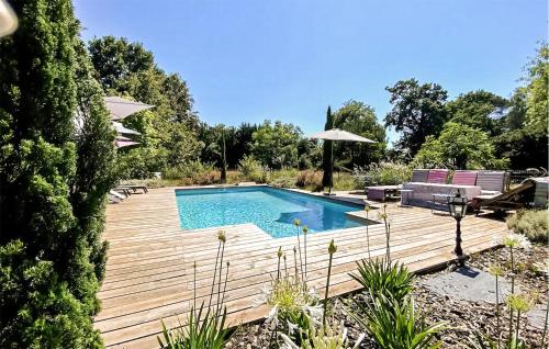 a swimming pool on a wooden deck with chairs and an umbrella at Superbe Maison Avec Piscine in Arengosse