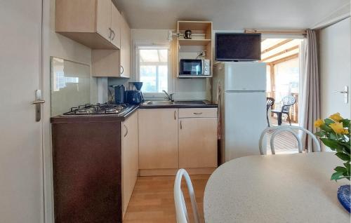 Elle comprend une petite cuisine équipée d'un réfrigérateur blanc et d'une table. dans l'établissement Mobilhome With Shared Pool, à Carnac