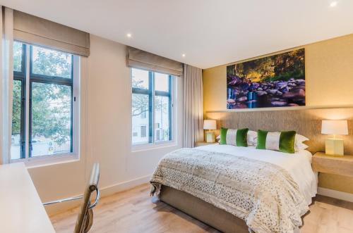 Un dormitorio con una cama grande y dos ventanas. en 107 Dorpstraat Boutique Hotel, en Stellenbosch