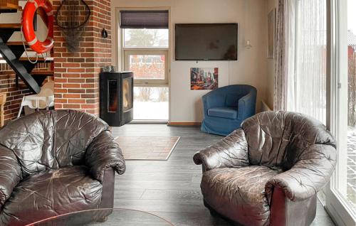 a living room with two leather chairs and a television at 3 Bedroom Gorgeous Home In Hesselager in Hesselager