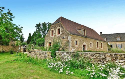 une ancienne maison en pierre avec un mur en pierre et des fleurs dans l'établissement Awesome Home In La Chapelle-Aubareil, à La Chapelle-Aubareil