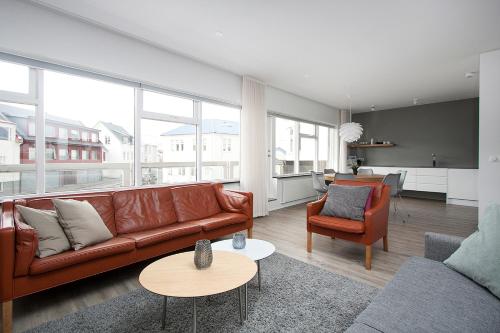 a living room with a brown leather couch and chairs at Reykjavík Central Apartments in Reykjavík