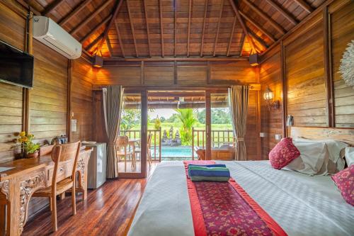 a bedroom with a bed and a table and a kitchen at Villa Kayu By Mardika in Ubud