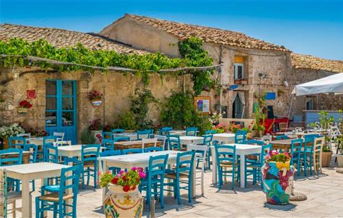 a group of tables and chairs in front of a building at Residenza Flamingo in Marzamemi