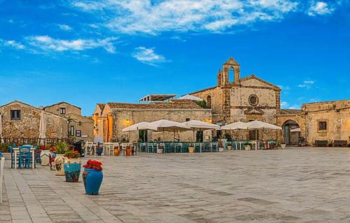 a courtyard with a large building with a clock tower at Residenza Flamingo in Marzamemi