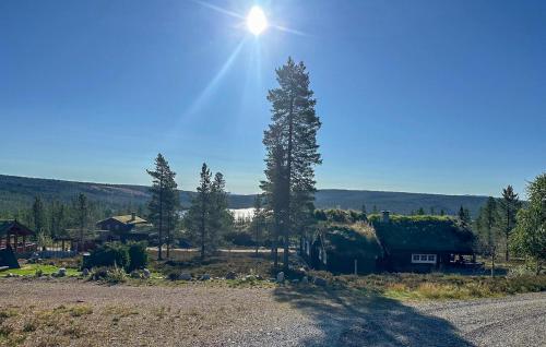 a tree in the middle of a field with a house at Beautiful Home In Jordet With Sauna in Jordet