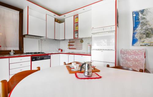 a kitchen with white cabinets and a table with a tea kettle on it at Cozy Home In Torre Dei Corsari in Torre Dei Corsari
