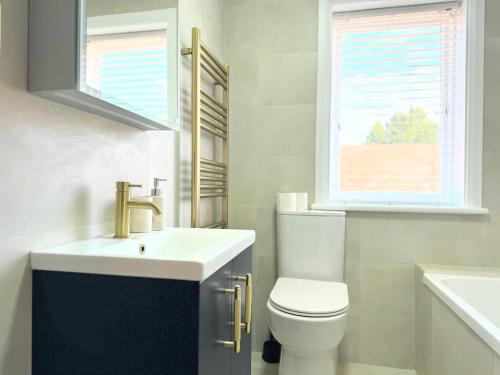 a bathroom with a sink and a toilet and a window at Entire Cosy Flat in Radlett - 3 Bedrooms -5 Beds - Sleeps 8 - Fast Train access into central London in Radlett