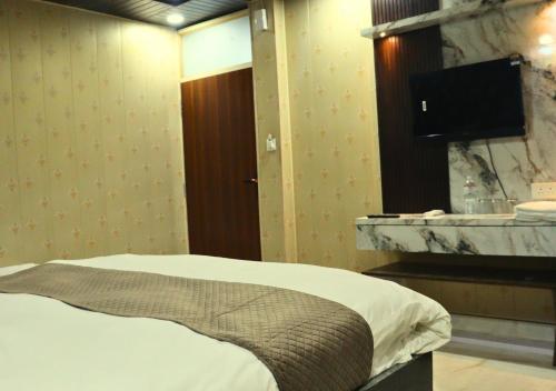 a hotel room with a bed and a television at Ganga Riverfront Rooms And Banquet in Prayagraj