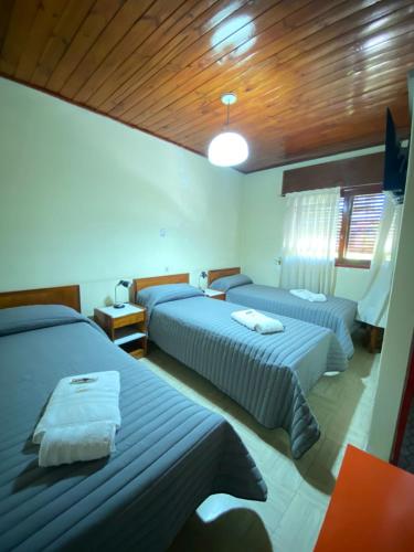 a bedroom with two beds and a wooden ceiling at Hotel Punto Sur Avenida in Malargüe