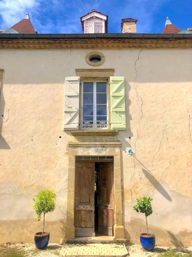 a building with two potted plants in front of a door at Domaine Le Berdoy in Montesquiou